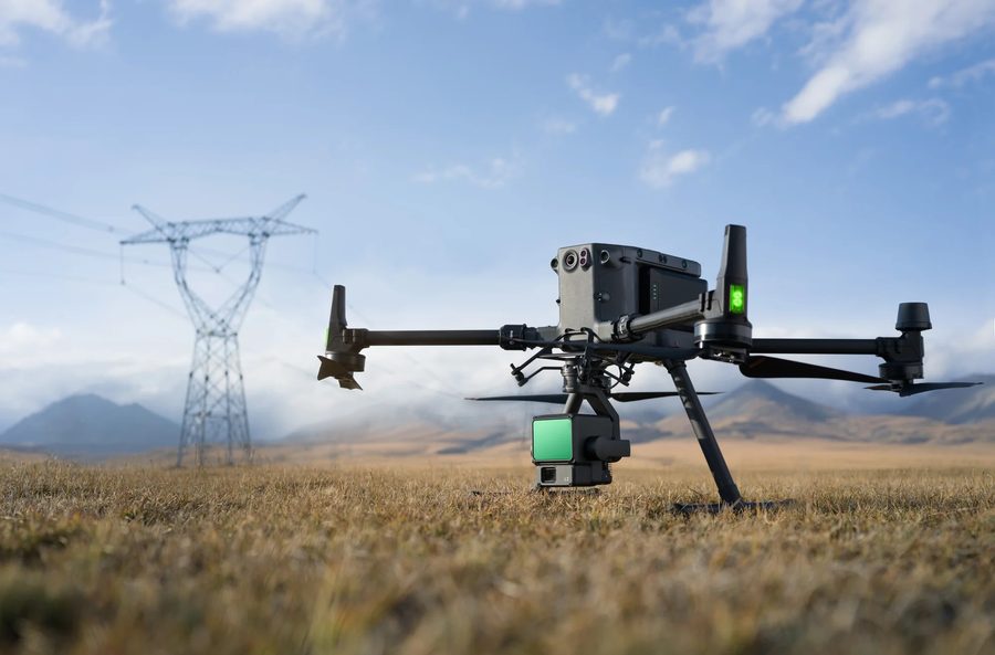 UAV with LiDAR payload on the ground beside a transmission tower