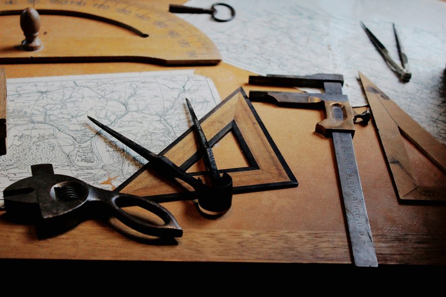 Historic survey drafting instruments and topographic maps on a wooden table